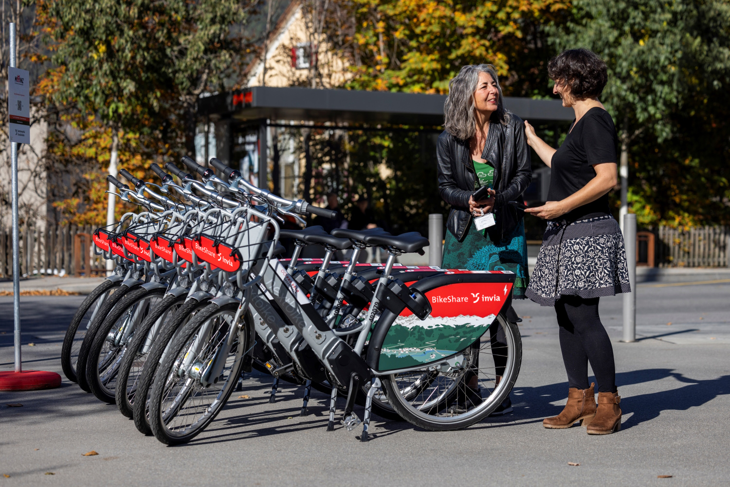 Zwei Frauen unterhalten sich neben einer invia bikeshare Station in Chur